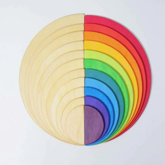 An 11-piece Waldorf rainbow wooden disc set arranged in a semi-circle pattern, transitioning from natural wood tones to vibrant colors like red, orange, yellow, green, blue, and purple.