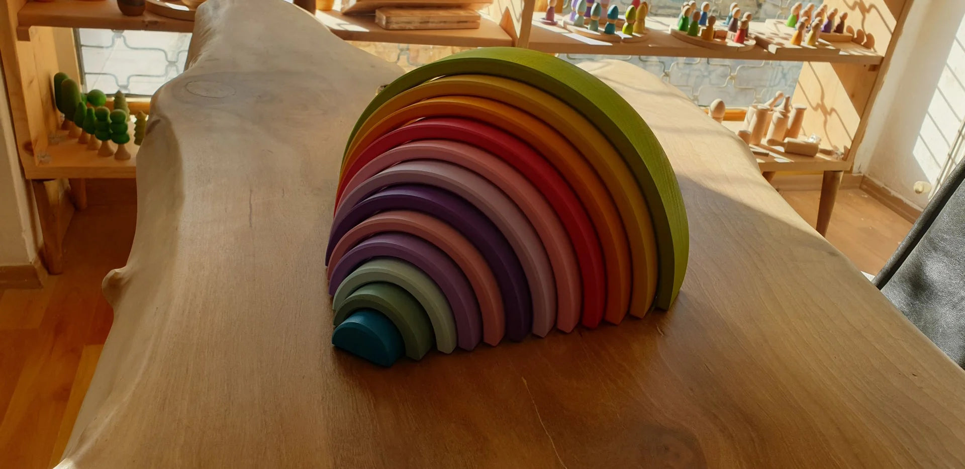 Waldorf-inspired rainbow wooden arch toy displayed on a wooden table
